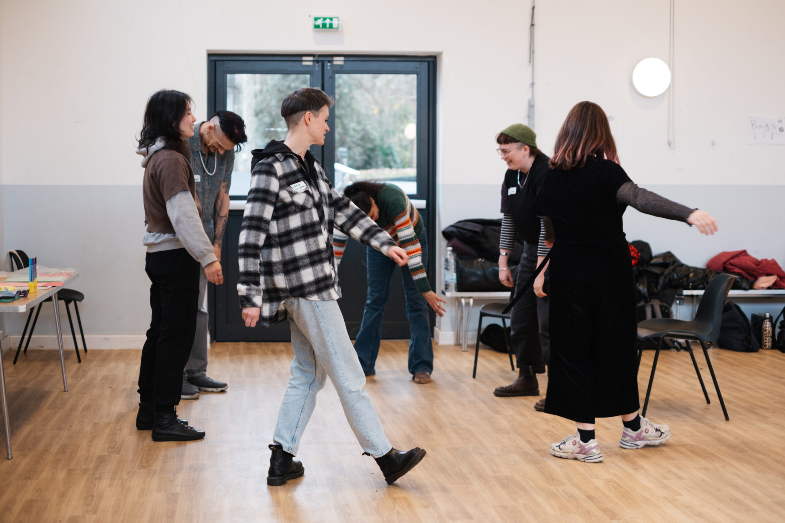 A number of people in an indoors space doing light stretching movements.
