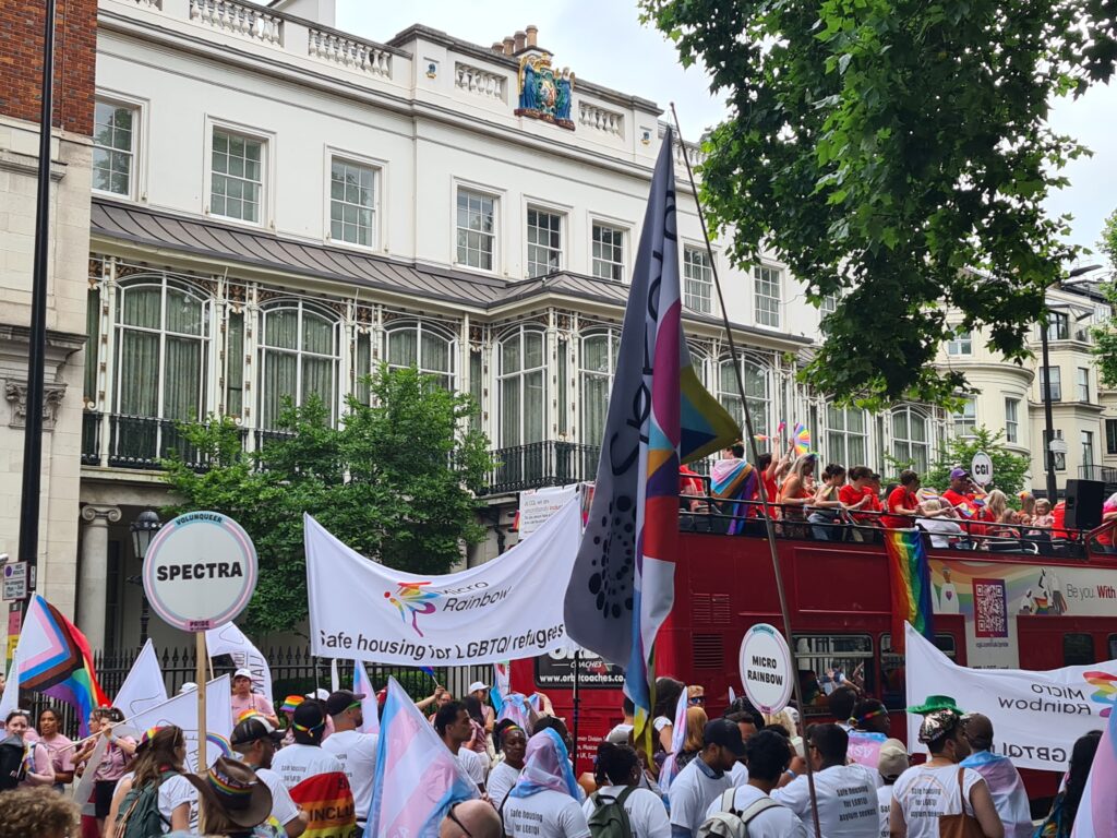 A group of people marching on the street, holding rainbow flags