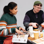 Two people doing crafts with paper and scissors on a table