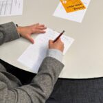Focus on someone's hands while writing on paper on a table