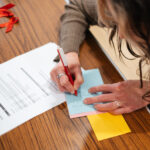 A close up of a person writing on a piece of paper. We can't see their face.